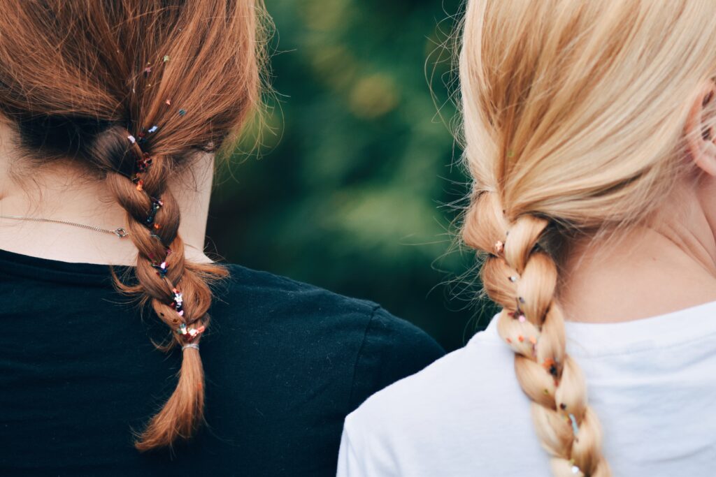 Two women with differently colored braided hair, symbolizing cultural unity.